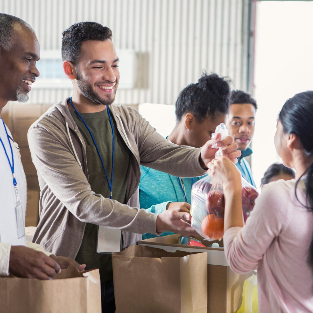 Male food bank volunteer passes out bags of fruit emergency giving